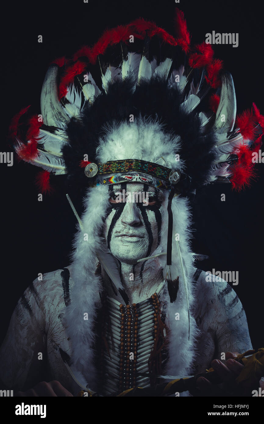 American Indian chief with feather headdress and traditional war ax ...