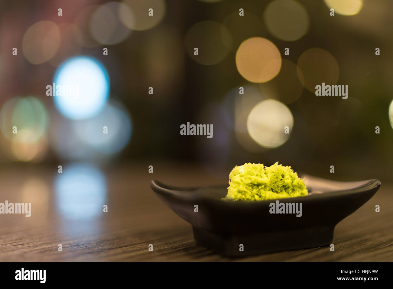 Wasabi in black saucer on wooden table with depth of field effect, Japanese food's condiment, bokeh background Stock Photo