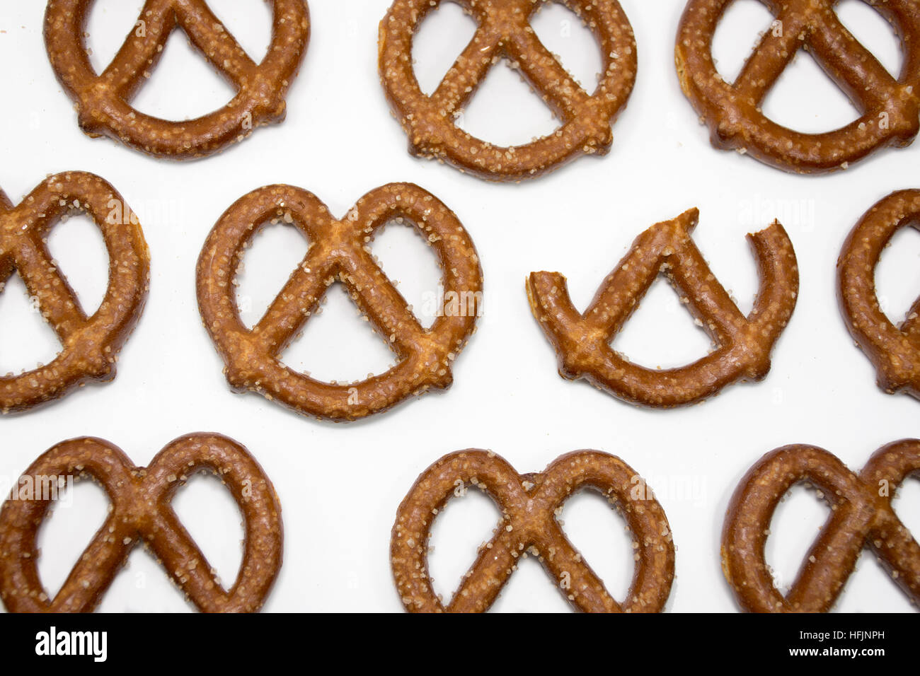 different concept - one eaten pretzel among a lot of perfect pretzels ordered on a white background Stock Photo