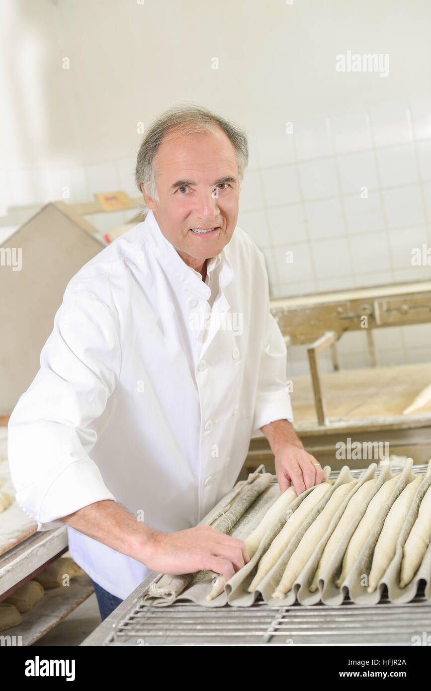 Baker rolling dough into baguettes Stock Photo Alamy