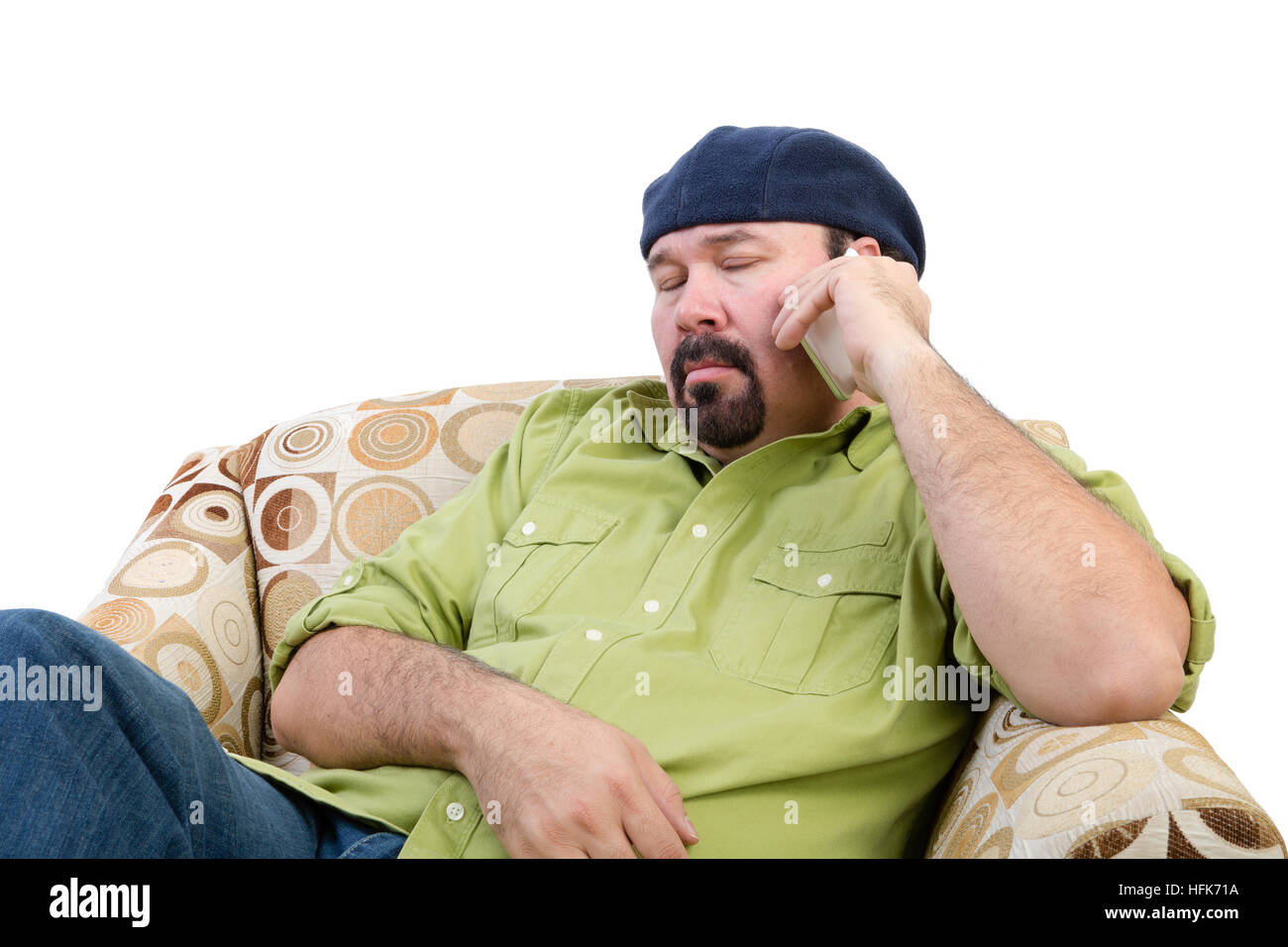 Bored overweight man in an armchair using a mobile, white background Stock Photo