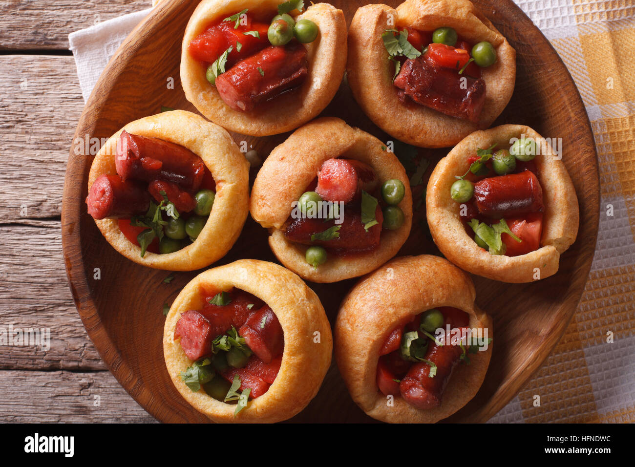 Yorkshire puddings stuffed with sausage and vegetables on a plate on a table closeup