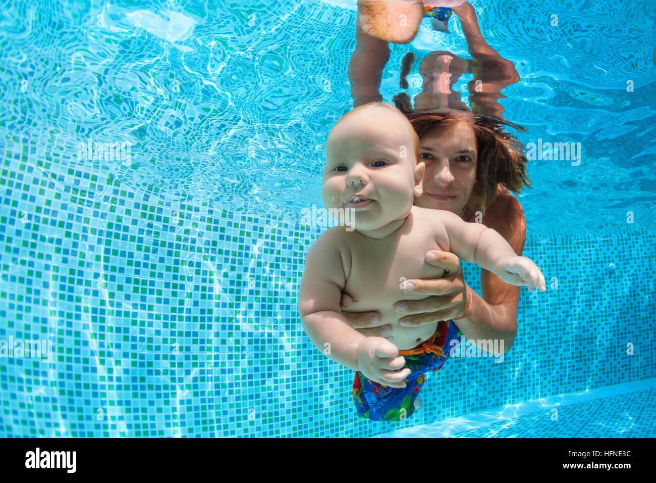 Family fitness. father hold in hands baby son learning dive underwater