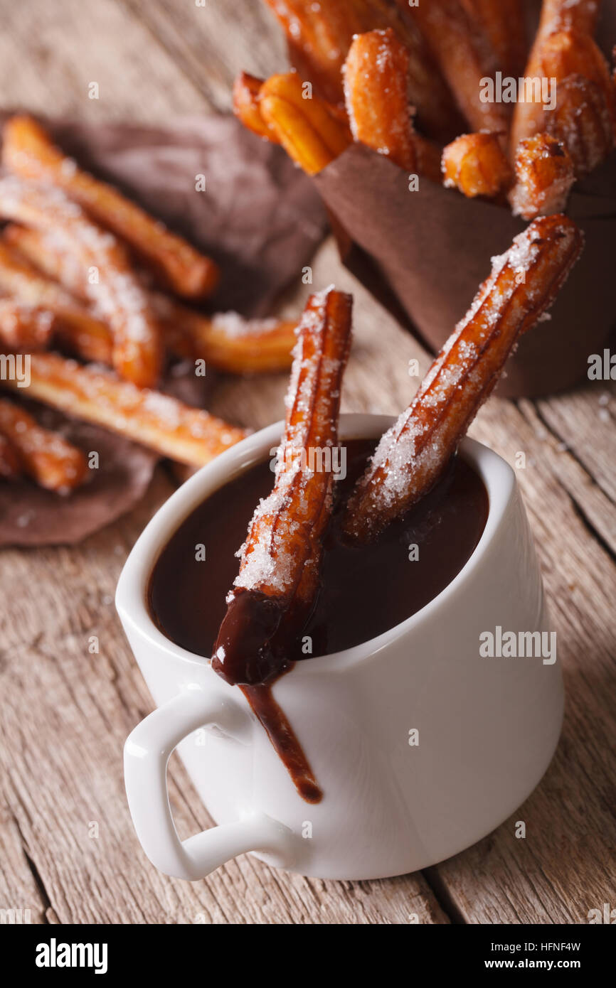 Tasty cookies churros dipped in chocolate in the cup on the table. vertical Stock Photo