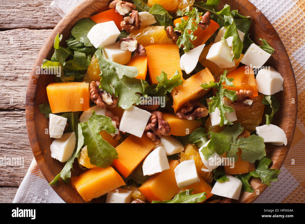 salad with persimmon, arugula, oranges and cheese close-up on the table. horizontal view from above Stock Photo