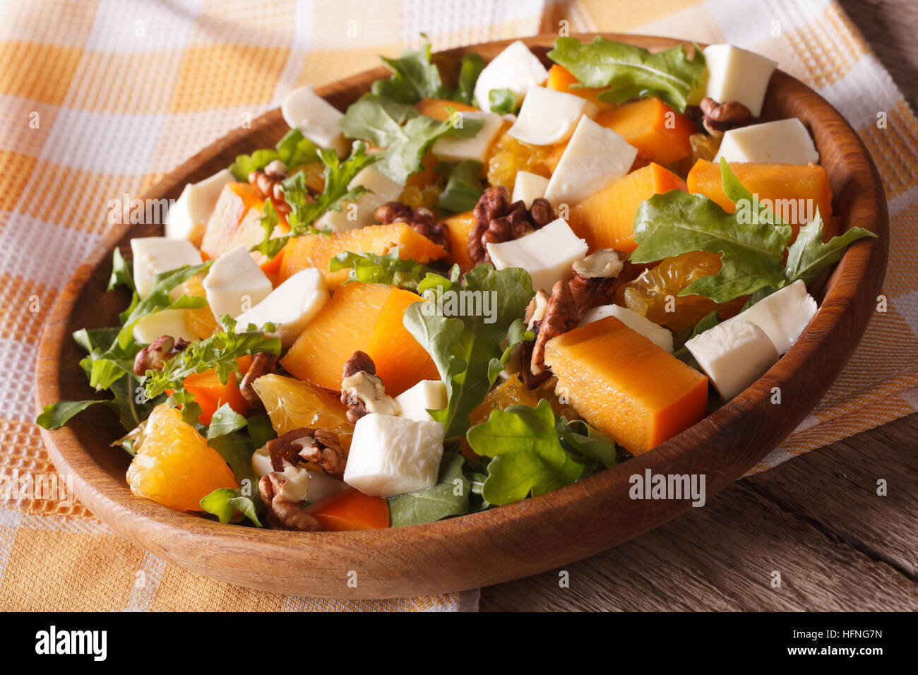 salad with persimmon, arugula, oranges and cheese close-up on a plate. horizontal Stock Photo
