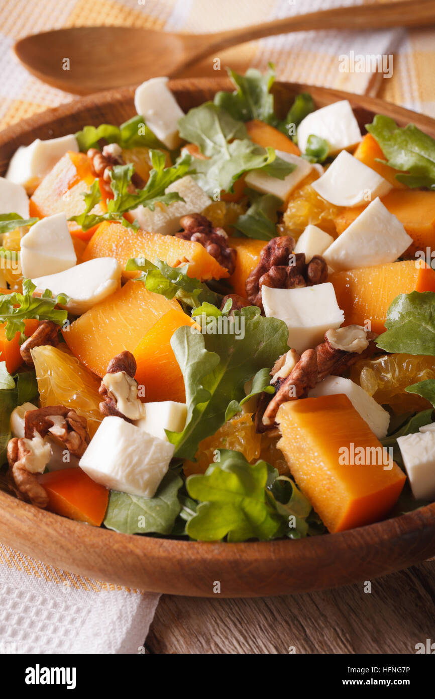 Healthy salad with persimmon, arugula and cheese macro on a plate. Vertical Stock Photo