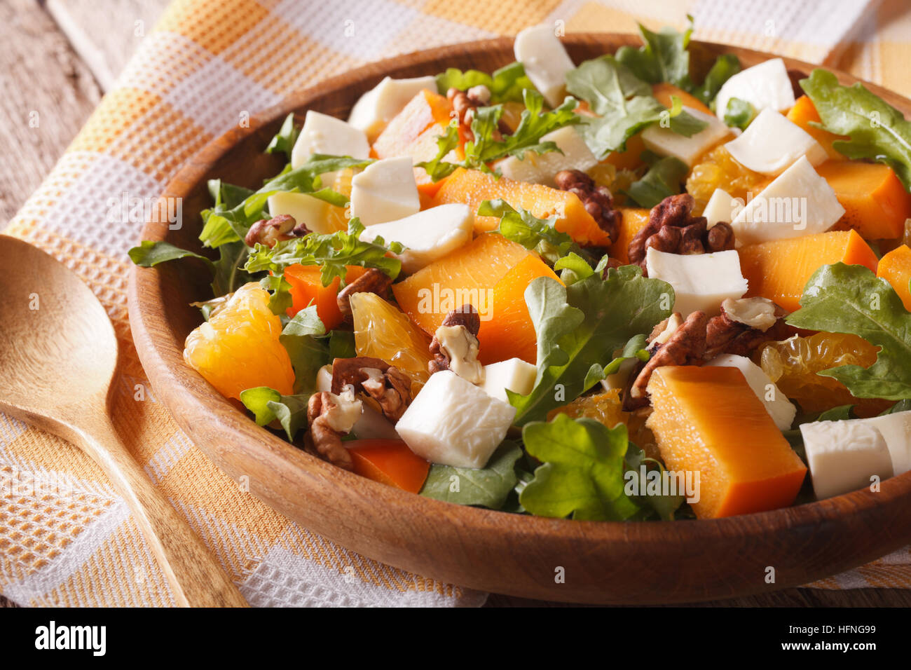 Healthy salad with persimmon, arugula and cheese close-up on a plate. horizontal Stock Photo