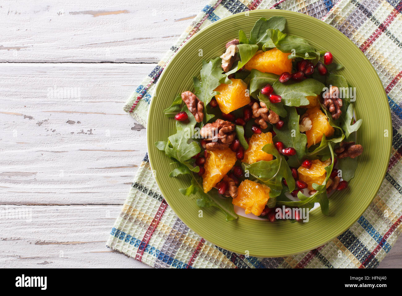 Delicious salad with pomegranate, oranges, walnuts and arugula on the table. horizontal top view Stock Photo