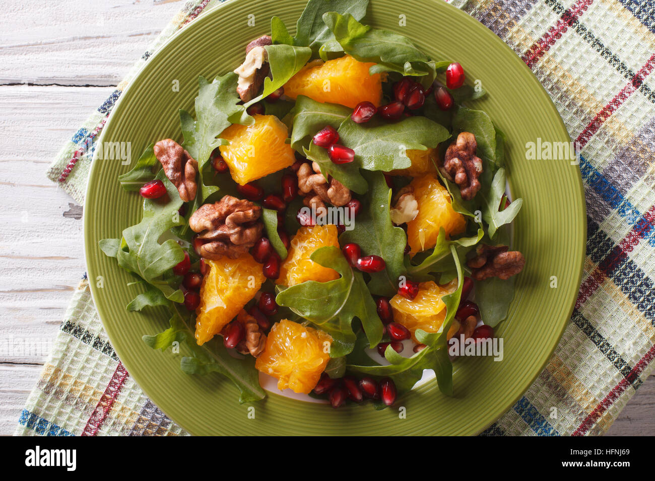 Delicious salad with pomegranate, oranges, walnuts and arugula close-up on the table. horizontal top view Stock Photo