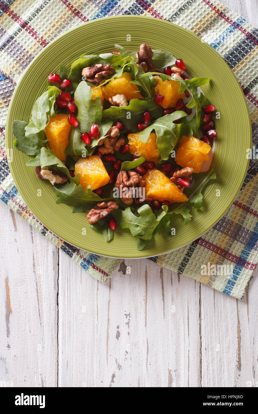 Delicious salad with pomegranate, oranges, walnuts and arugula on the table. vertical top view Stock Photo