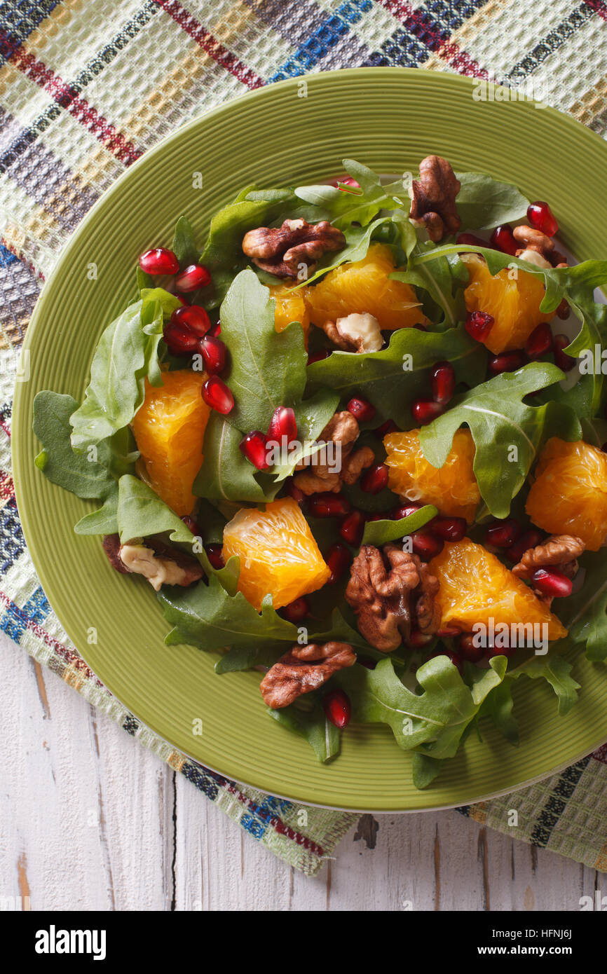 Healthy salad with orange, arugula and pomegranate close-up on a plate. vertical top view Stock Photo
