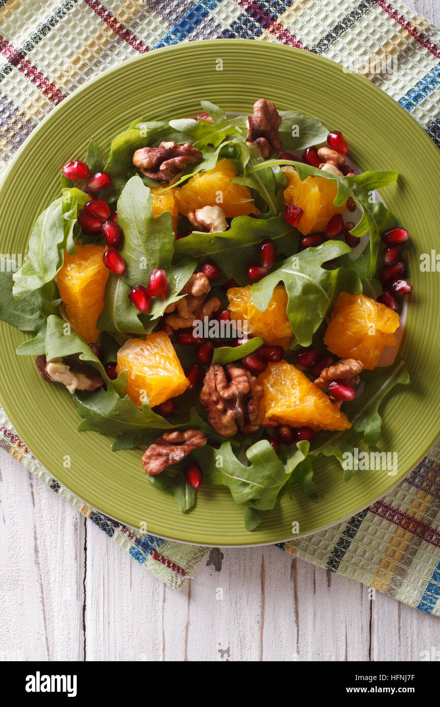 Delicious salad with pomegranate, oranges, walnuts and arugula close-up on the table. vertical top view Stock Photo