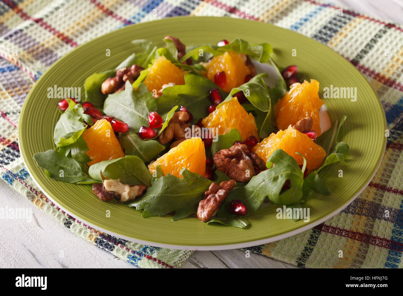 Delicious salad with pomegranate, oranges, walnuts and arugula close-up on the table. horizontal Stock Photo