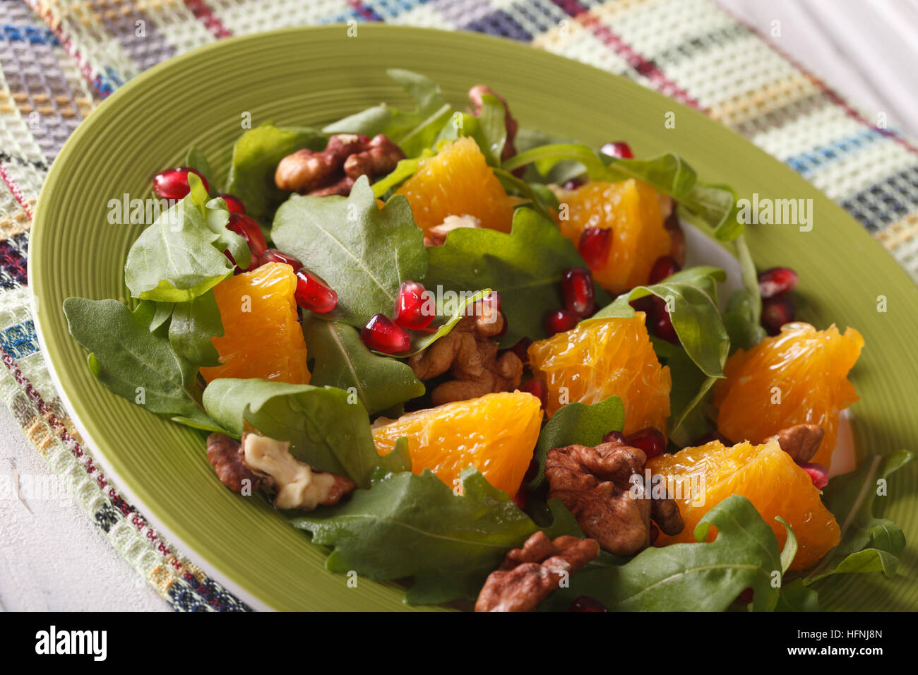 Dietary salad with pomegranate, orange and arugula close-up on a plate. horizontal Stock Photo