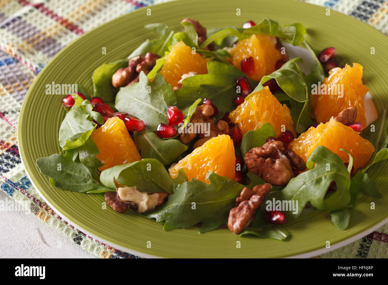Healthy salad with pomegranate, oranges, walnuts and arugula close-up on a plate. horizontal Stock Photo
