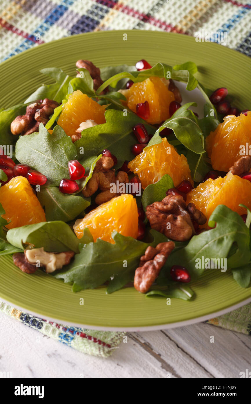 Fresh salad with pomegranate, orange and arugula close-up on a plate. Vertical Stock Photo