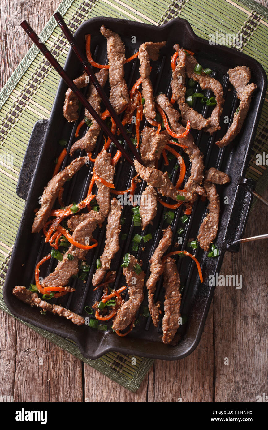 Korean Food: Bulgogi beef with carrot and onion on grill pan closeup. vertical top view Stock Photo