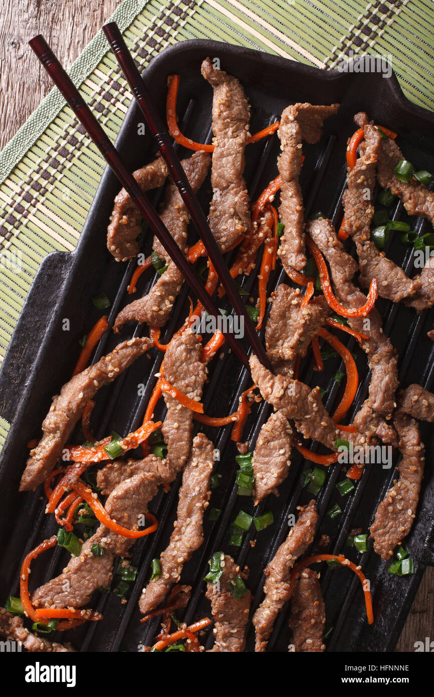 Korean Food: Bulgogi beef with carrot and onion on grill pan macro. vertical top view Stock Photo