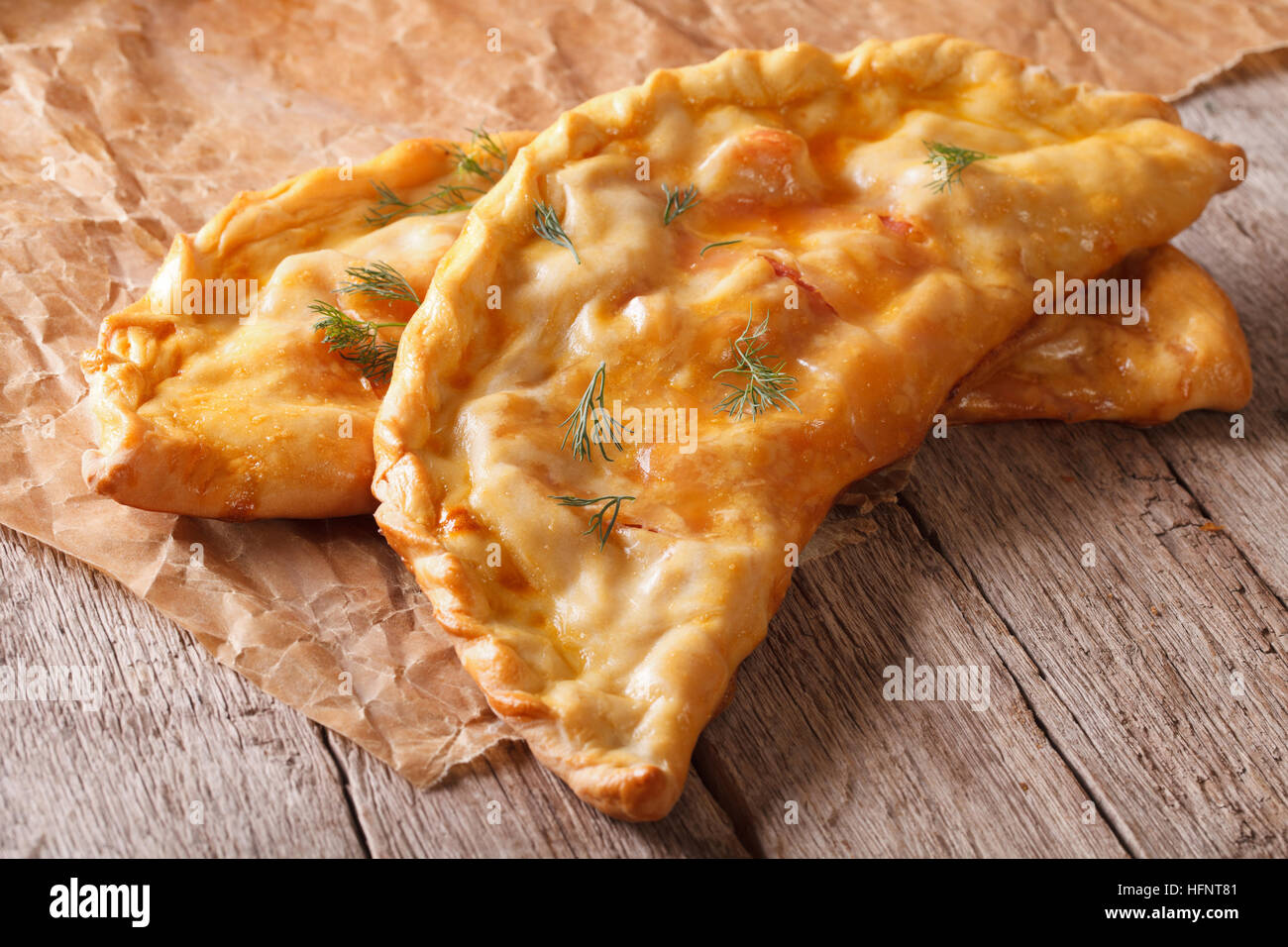 Pizza calzone close-up on a paper on the table. horizontal Stock Photo