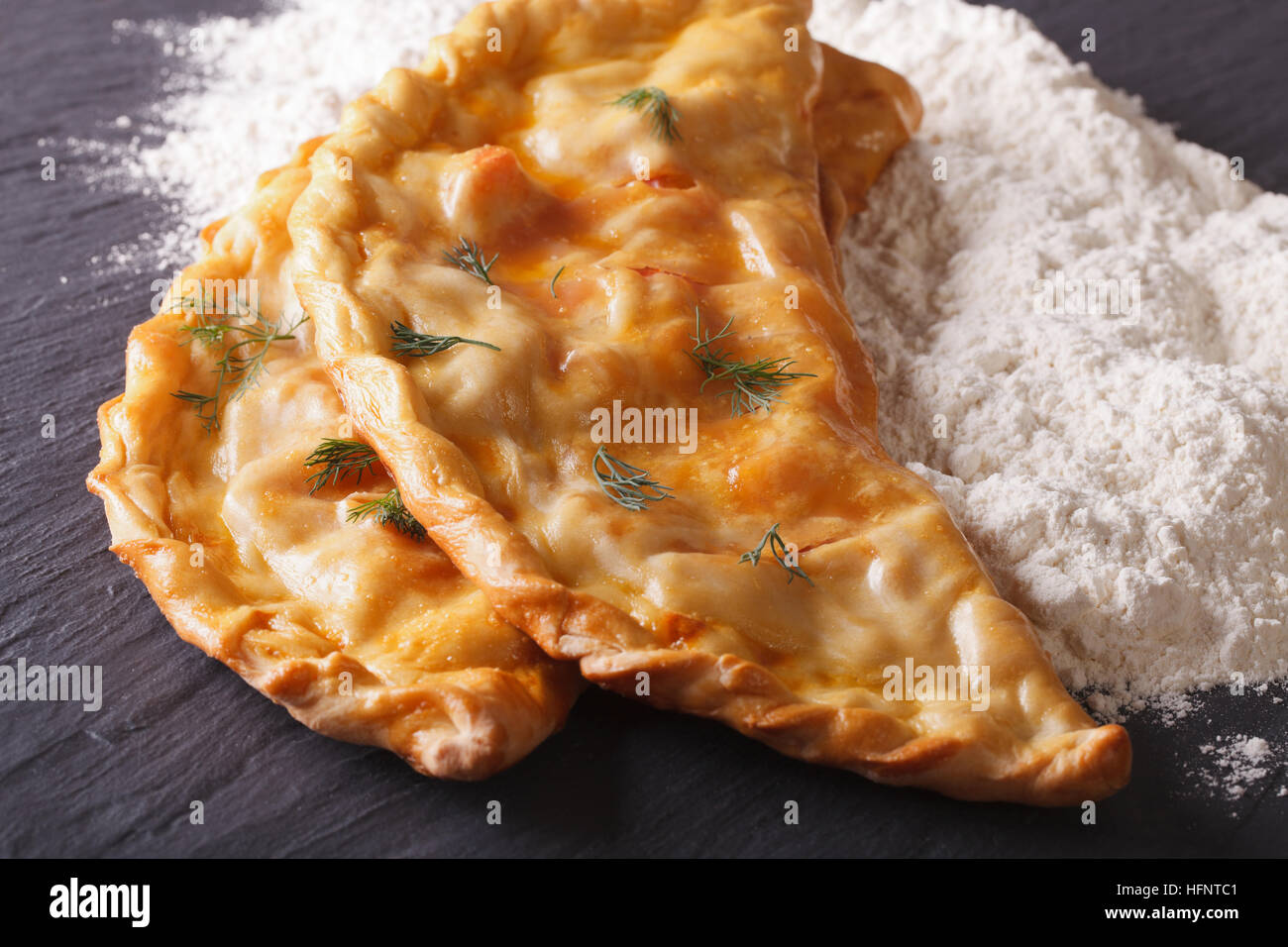 Italian pizza calzone and white flour close-up on the table. horizontal Stock Photo