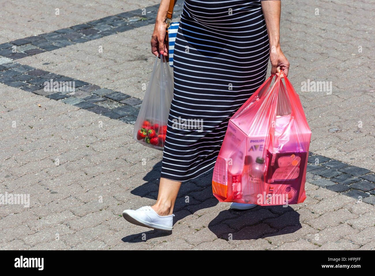 Shopper Woman walking with plastic bags takes away goods from the supermarket, plastic bags shopping Stock Photo