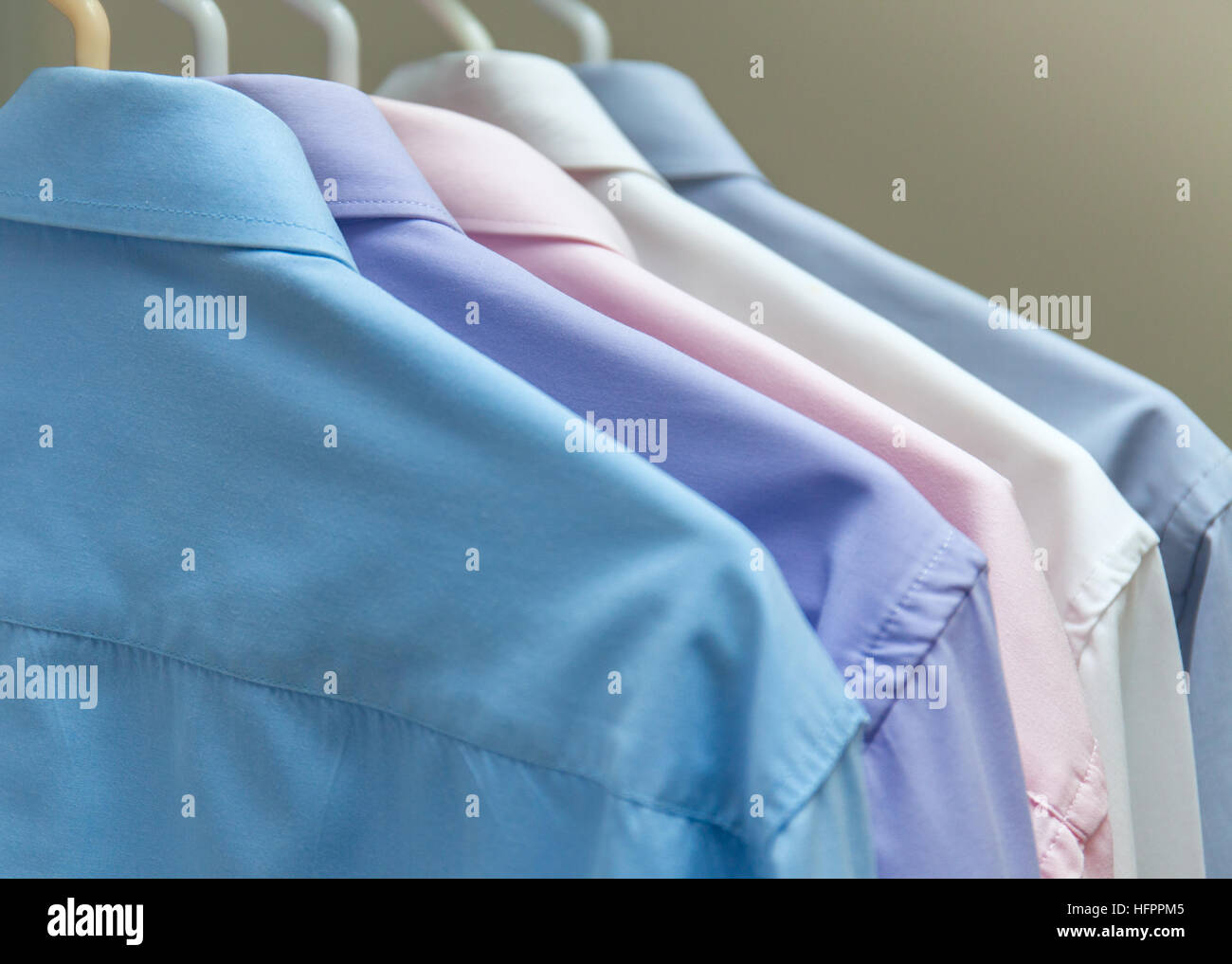 bright men's shirts hanging on hangers  gray background Stock Photo