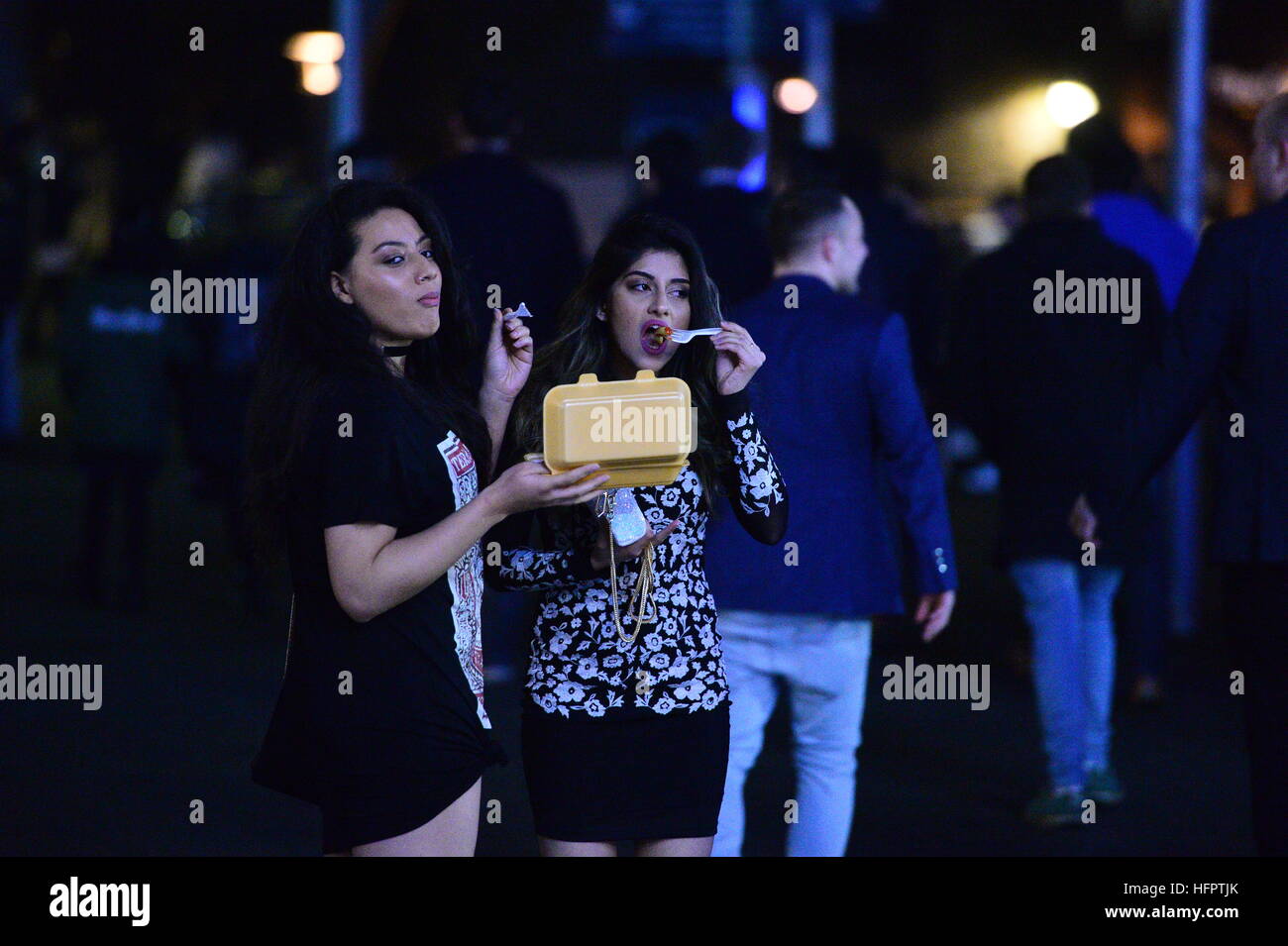 People eat takeaway food in Bristol city centre as they wait to see in the New Year. Stock Photo