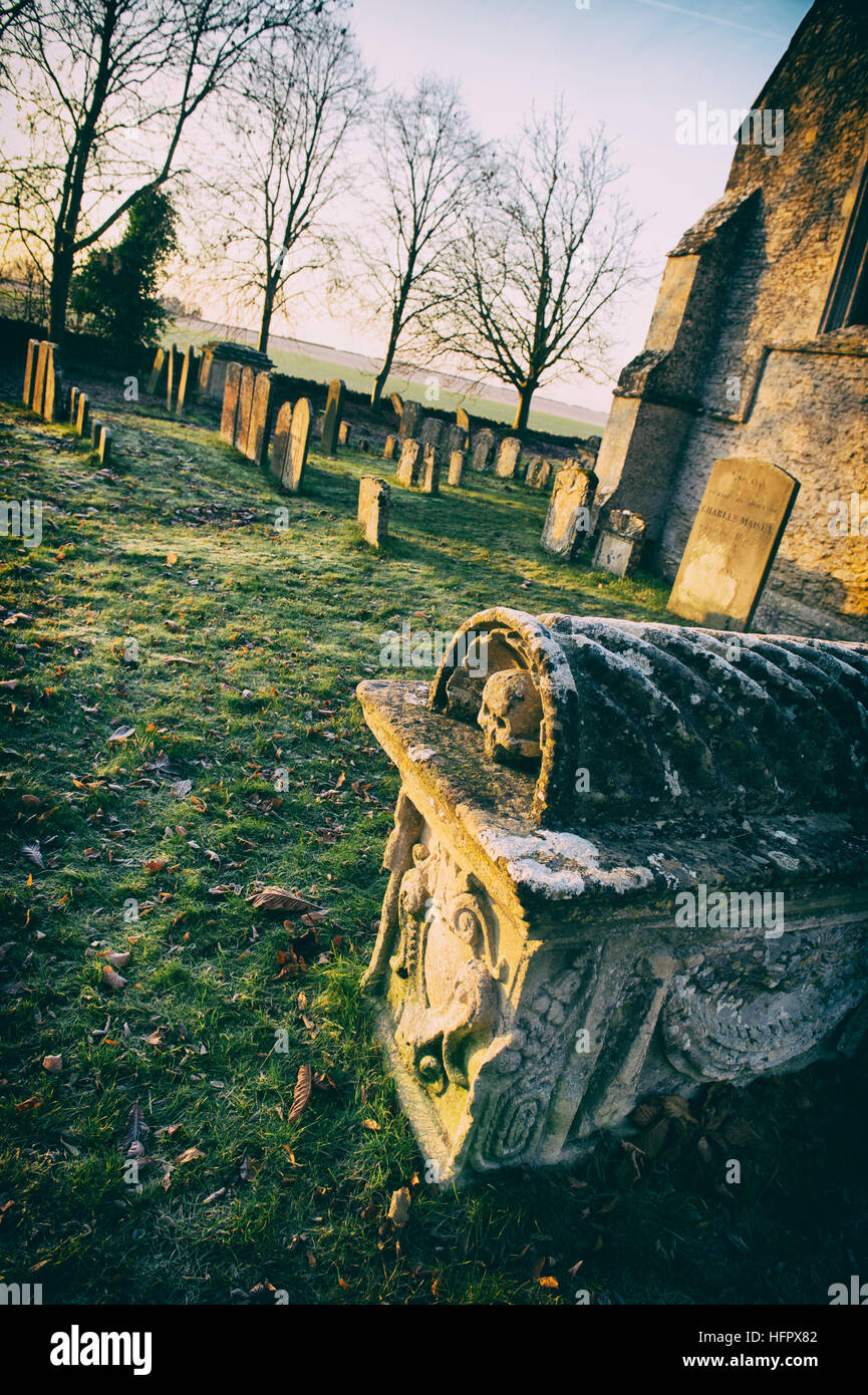 Holy Rood Church and tomb in the early morning winter sunlight. Shilton, Nr Burford, Cotswolds, Oxfordshire, England. Stock Photo