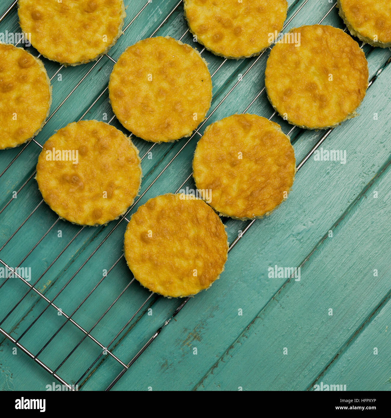 Coconut orange biscuit cake cut outs on cooling net, turquoise background Stock Photo