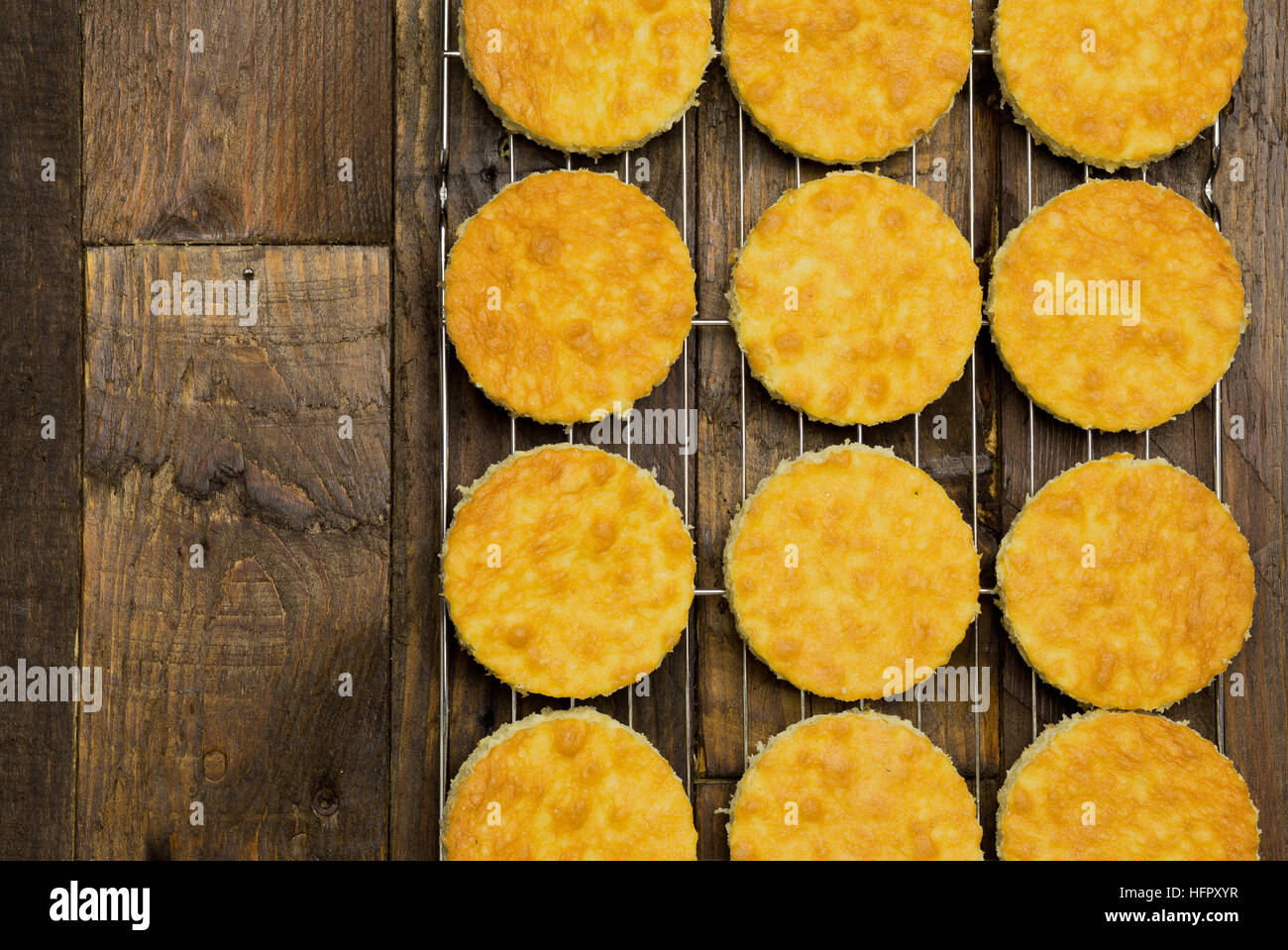 Coconut orange biscuit cake cut outs on cooling net, dark brown background Stock Photo