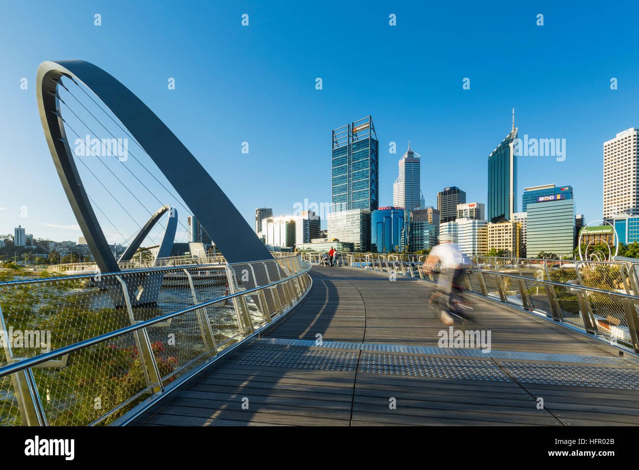 Cyclist crossing the Elizabeth Quay bridge with the city skyline beyond, Perth, Western Australia, Australia Stock Photo