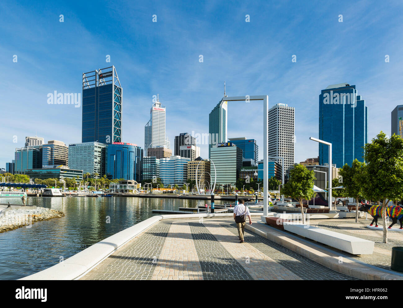 City worker walking along Elizabeth Quay with the city skyline beyond, Perth, Western Australia, Australia Stock Photo