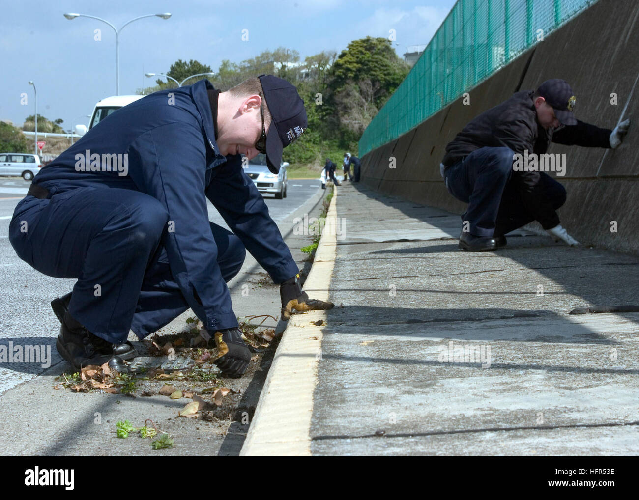 060421-N-5686B-002 Yokosuka, Japan (April 21, 2006) - Storekeeper 1st Class Eric Beals stationed at Fleet and Industrial Supply Center, pulls weeds along the side of the road at Commander Fleet Activities Yokosuka, Japan. CFAY held a spring clean-up which focused on areas of the base that have been neglected. U.S. Navy photo by PhotographerÕs Mate 1st Class Crystal Brooks (RELEASED) US Navy 060421-N-5686B-002 Storekeeper 1st Class Eric Beals stationed at Fleet and Industrial Supply Center, pulls weeds along the side of the road at Commander Fleet Activities Yokosuka, Japan Stock Photo