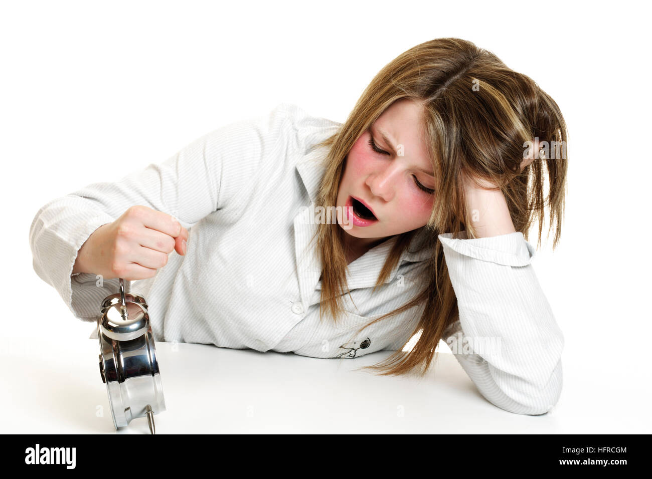 Girl wearing pajamas hitting an alarm clock, yawning Stock Photo