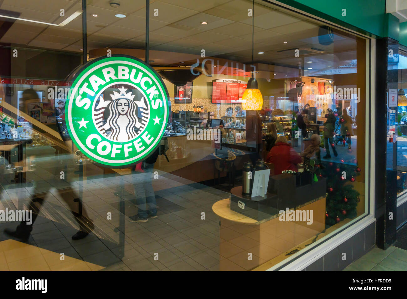 Starbucks Coffee Shop in a shopping arcade with people hurrying by reflected in the window Stock Photo