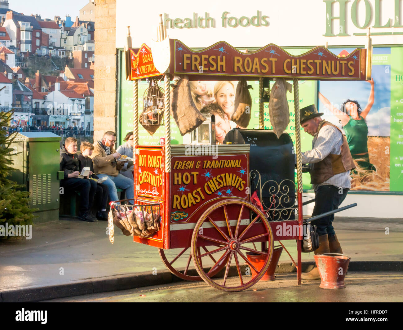 A Hot Roast Chestnut street vendor loading nuts into his portable oven