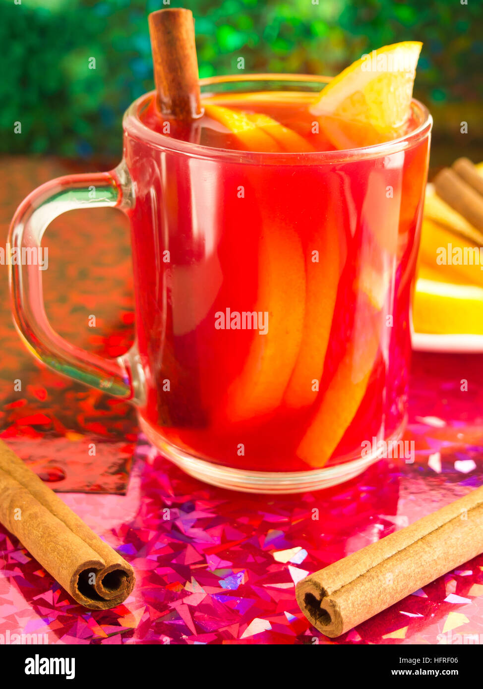 Glass mug with citrus mulled wine, cinnamon and orange to bright shiny background with blur and shallow depth of focus Stock Photo