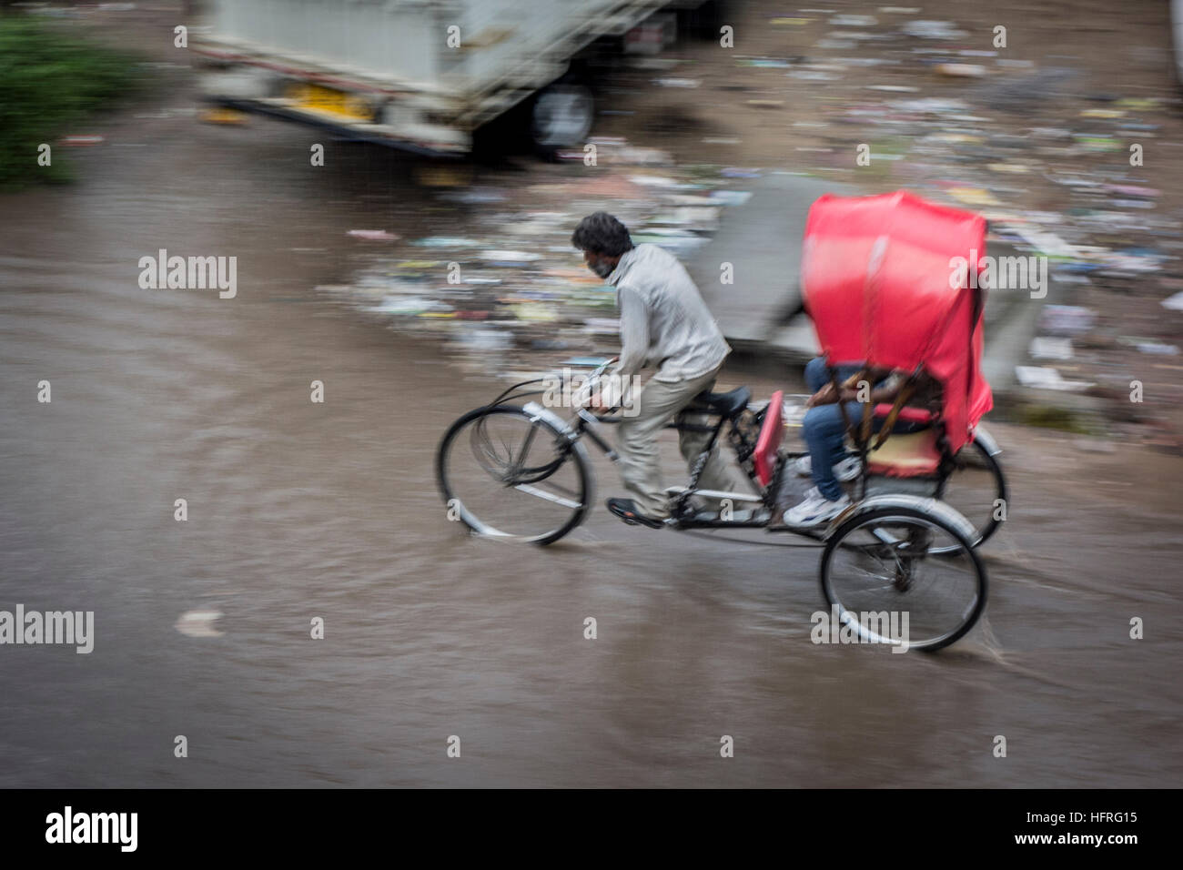 Bicycle rickshaw pedaling through flooding in the streets (Jaipur, India). Stock Photo