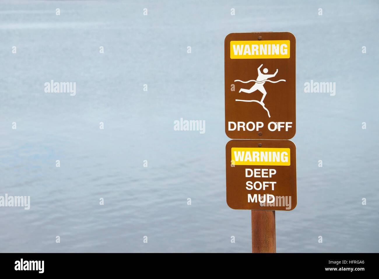 Warning drop off sign near cliff by waters edge. Water in background Stock Photo