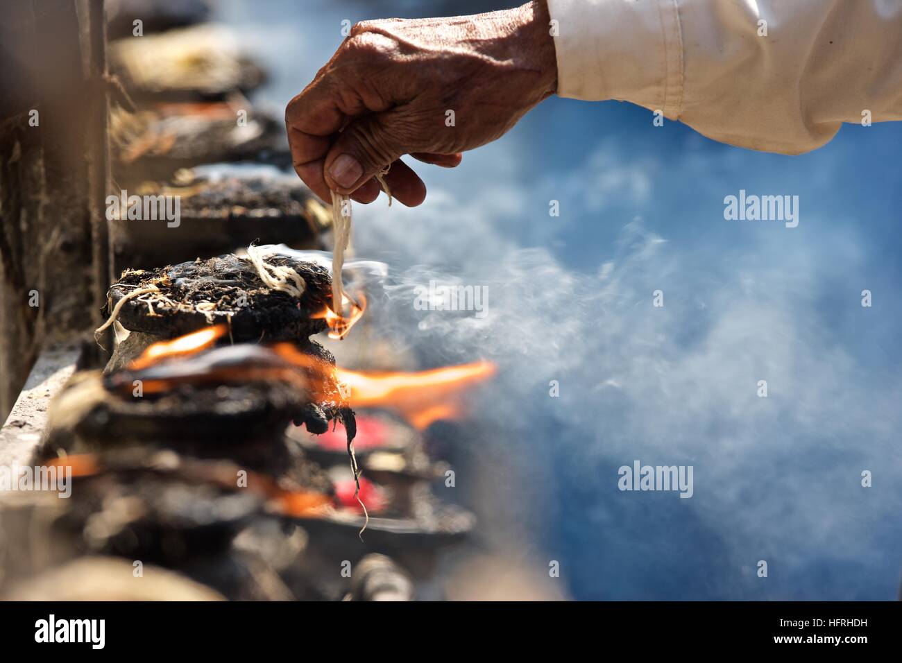 Kathmandu Bhaktapur temple worship oil lamps string fire smoke hand