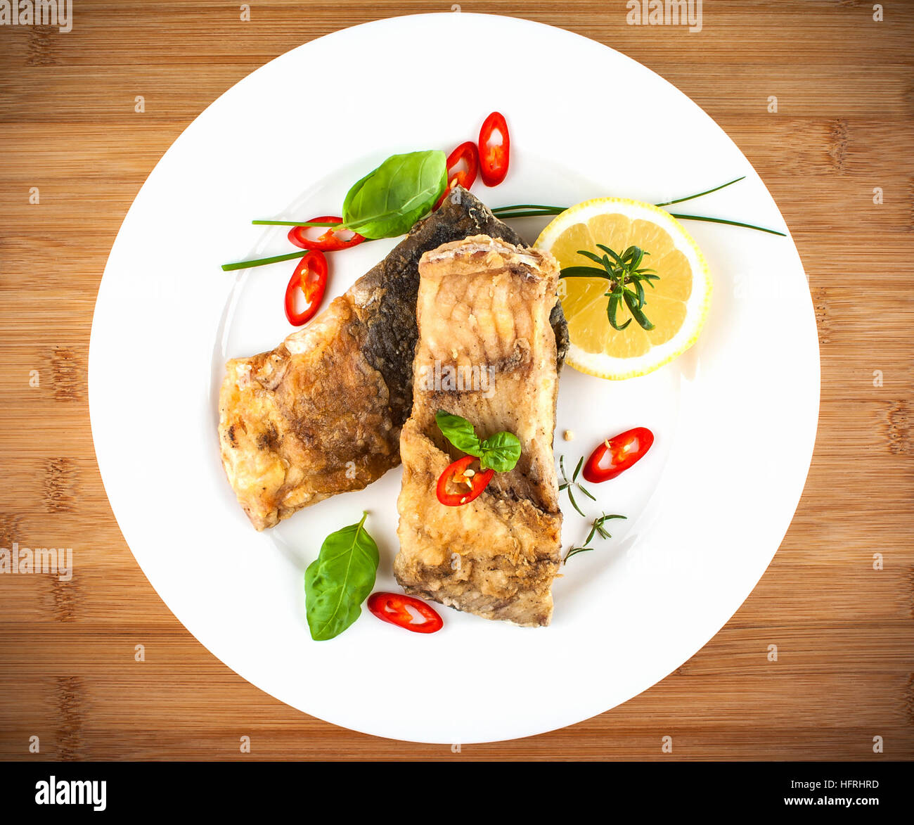 Fried fish on white plate bamboo board, top view Stock Photo