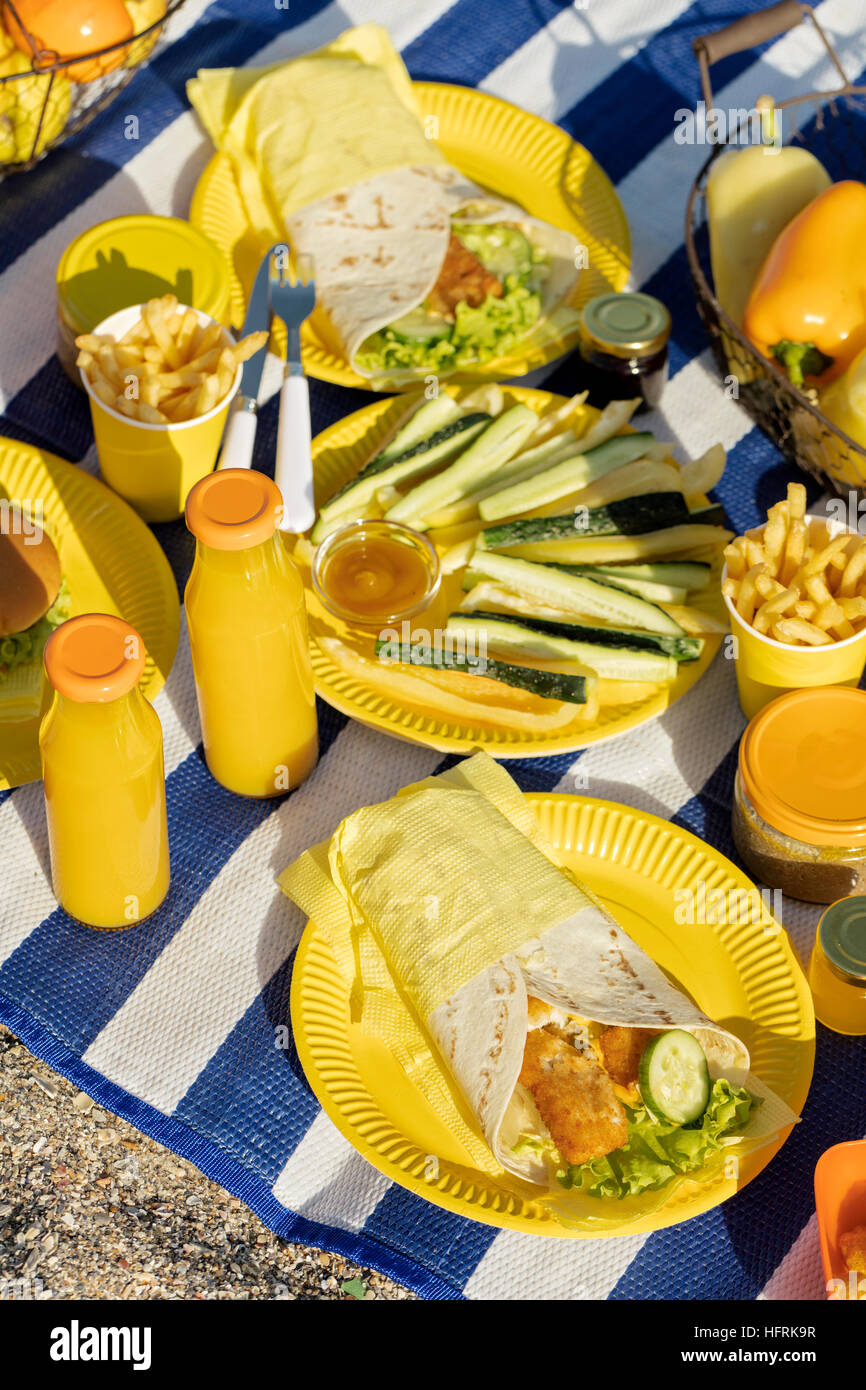 Summertime. A picnic on the beach. Burgers and pitas, vegetables and fruits. Selective focus. Stock Photo
