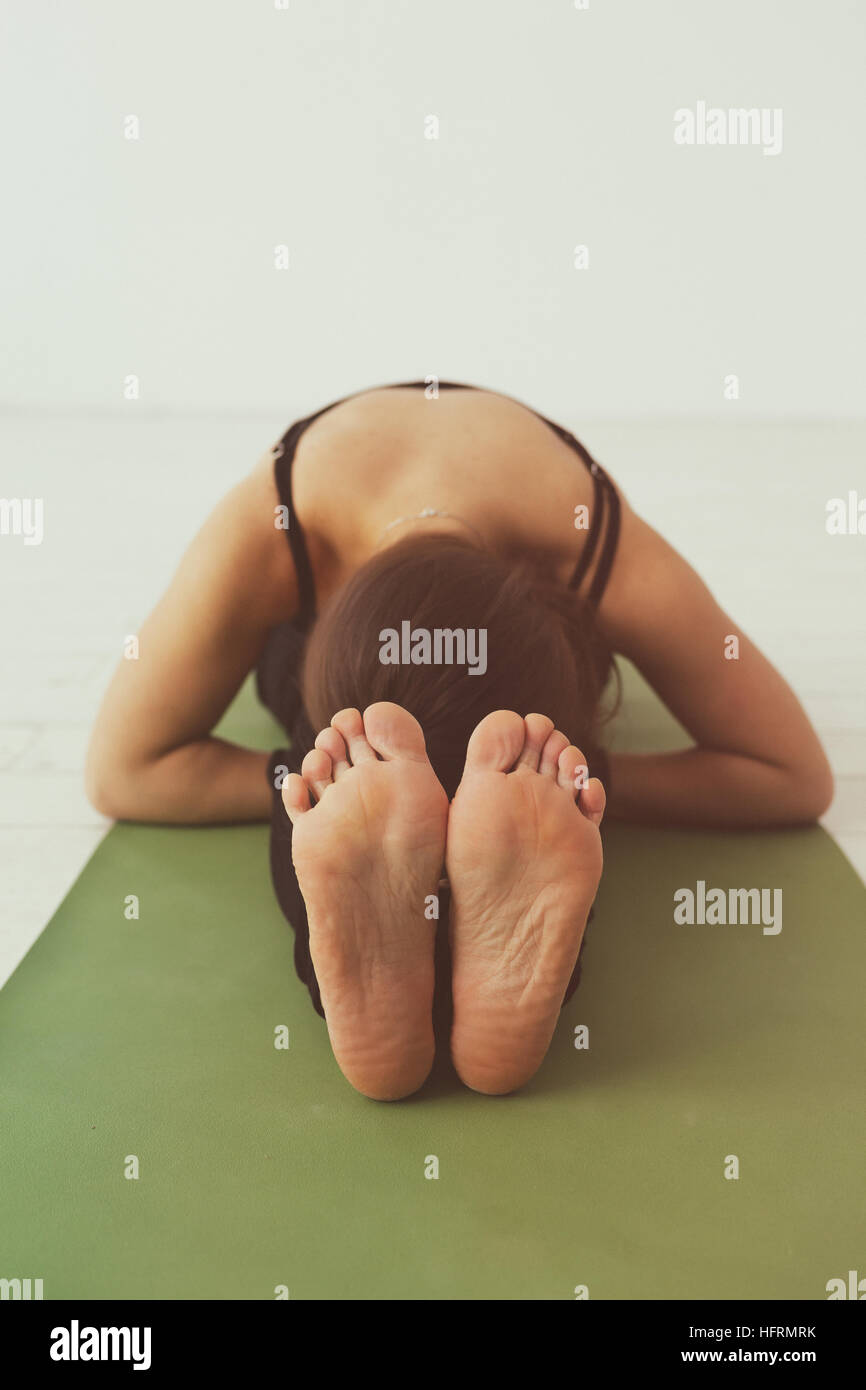Seated forward bend. Intense dorsal stretch girl is doing yoga while ...