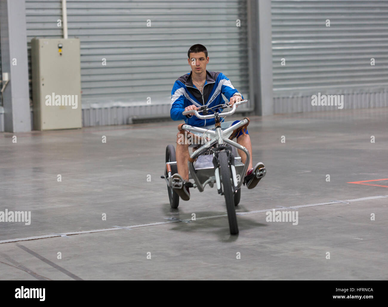 Unrecognized visitor tests modern tricycle electric bike at First International Trade Show of Electric Vehicles Plug-In Ukraine. Stock Photo