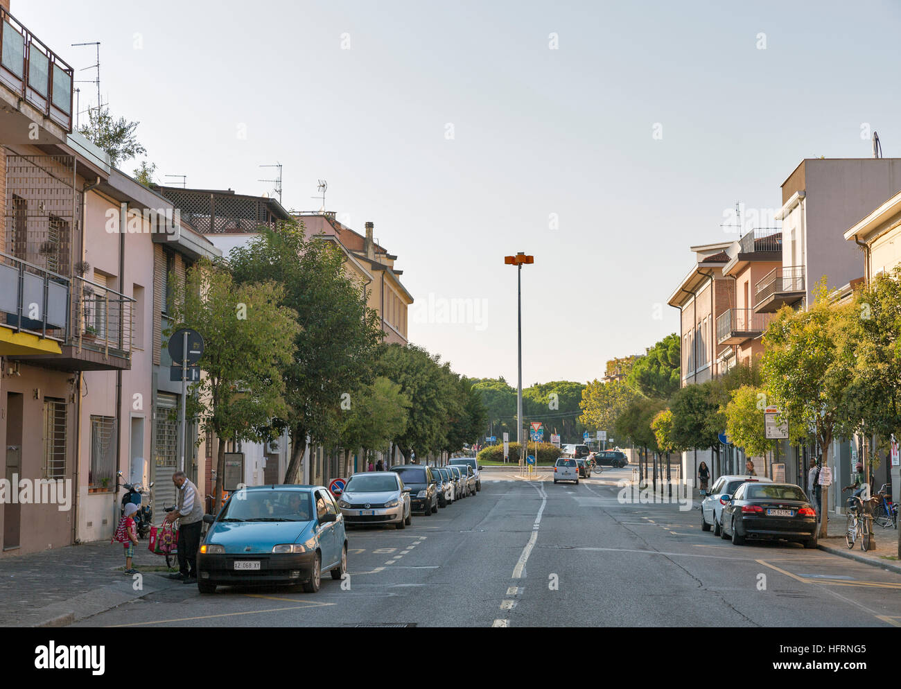 People on Via dei Mille street with old buildings and parked cars. Stock Photo
