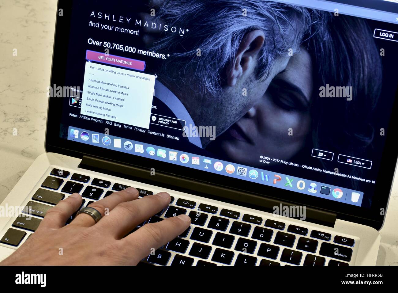 An Apple Macbook Pro displayed on a white marble surface with a married man viewing the Ashley Madison hookup website Stock Photo