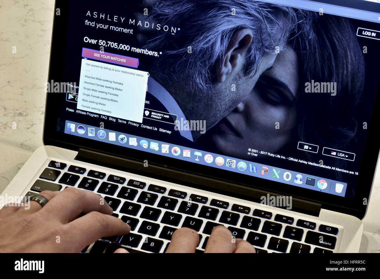 An Apple Macbook Pro displayed on a white marble surface with a married man viewing the Ashley Madison hookup website Stock Photo