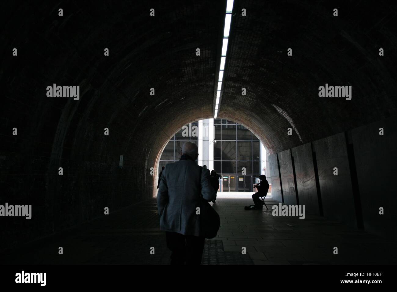 Musician and man walking in dark tunnel Stock Photo