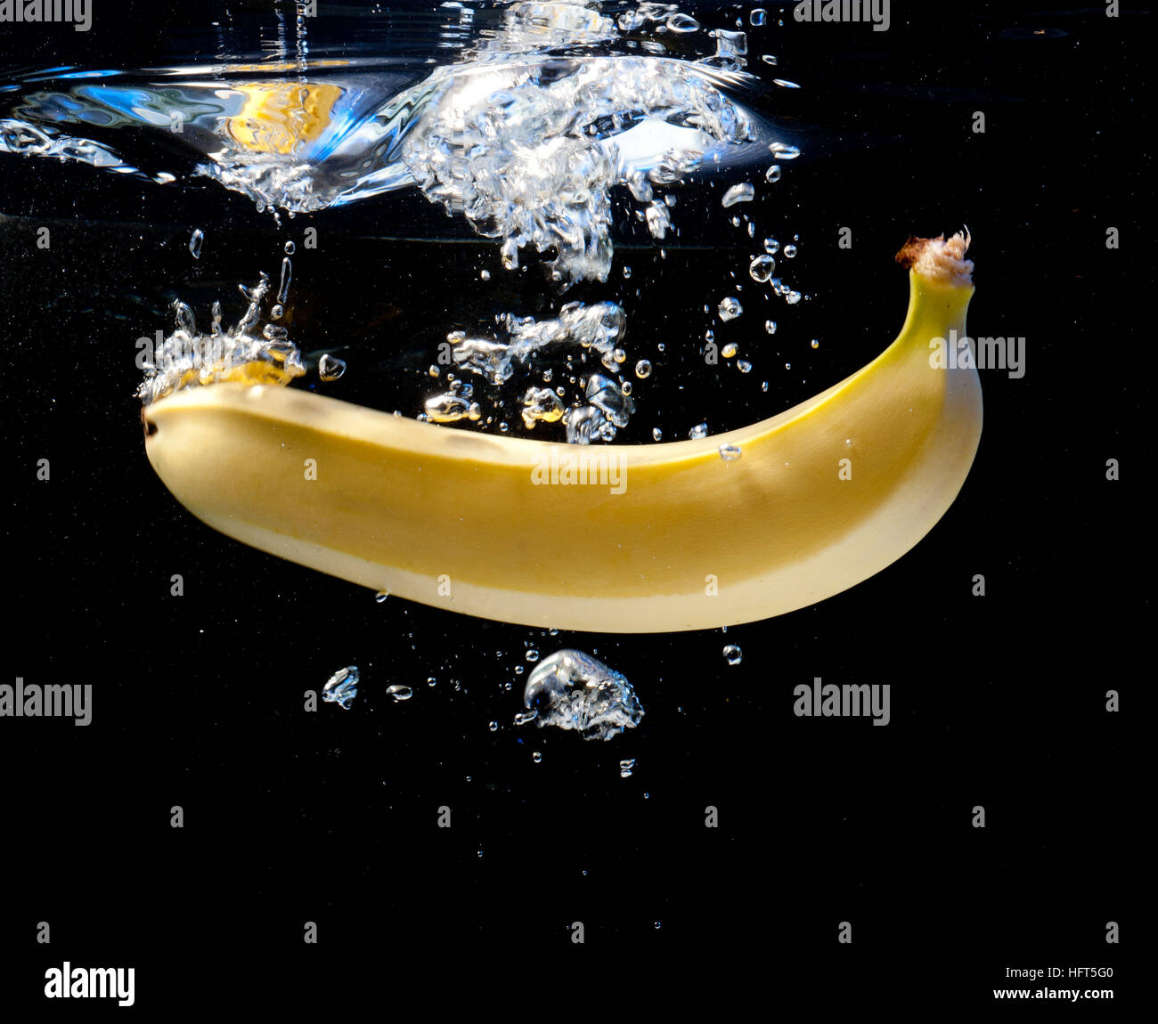 Banana fell into the water on a black background Stock Photo